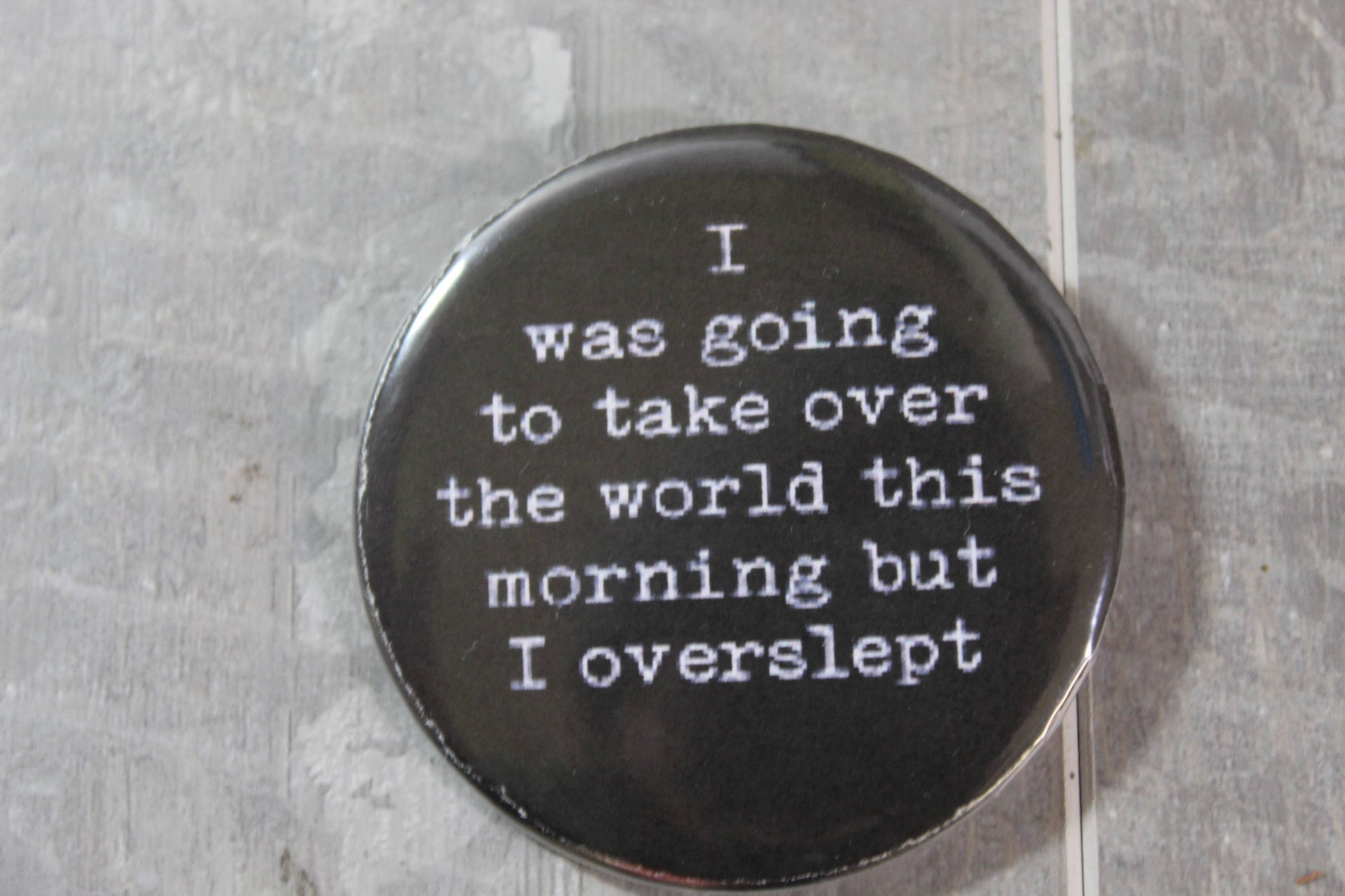 black pin back button with words i was going to take over the world this morning but I overslpt