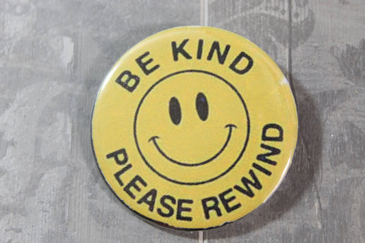 smile face metal pin back button with words around Be Kind Rewind