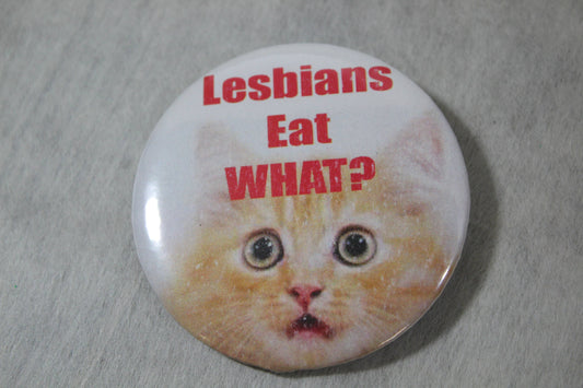 pin back button with surprised cat face saying lesbians eat what