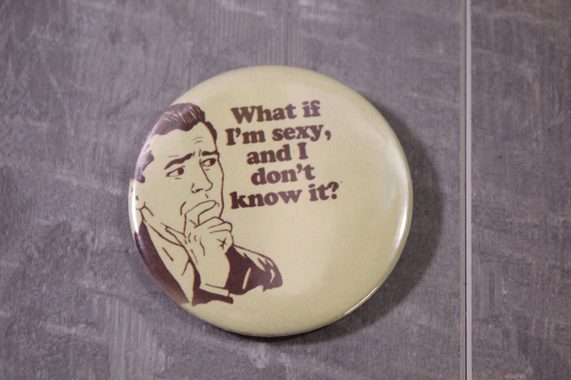 tan colored pin back button that says what if im sexy and i don't know it